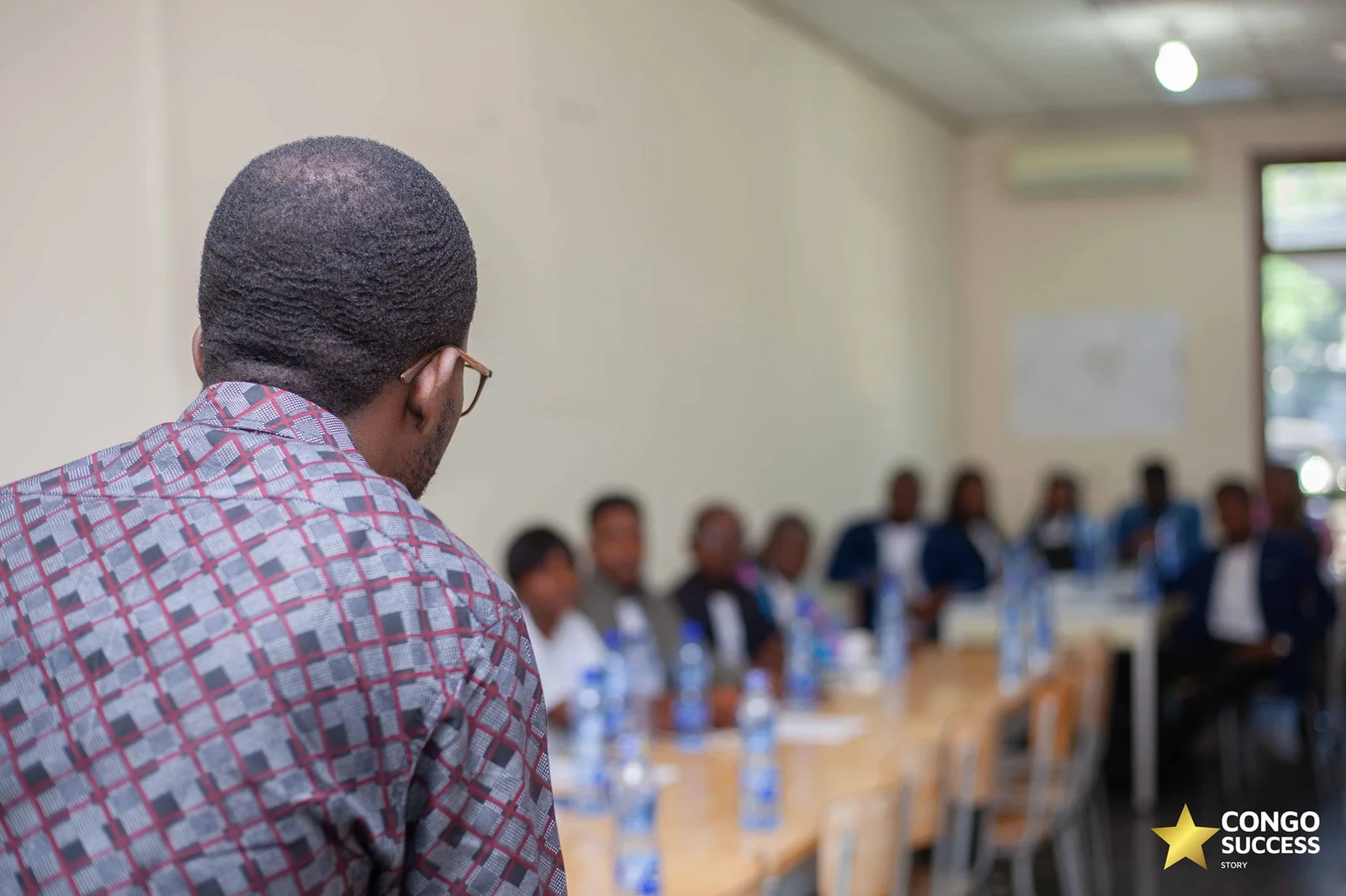 Vue d’un intervenant face aux participants autour d’une table, photographie Congo Success Story.