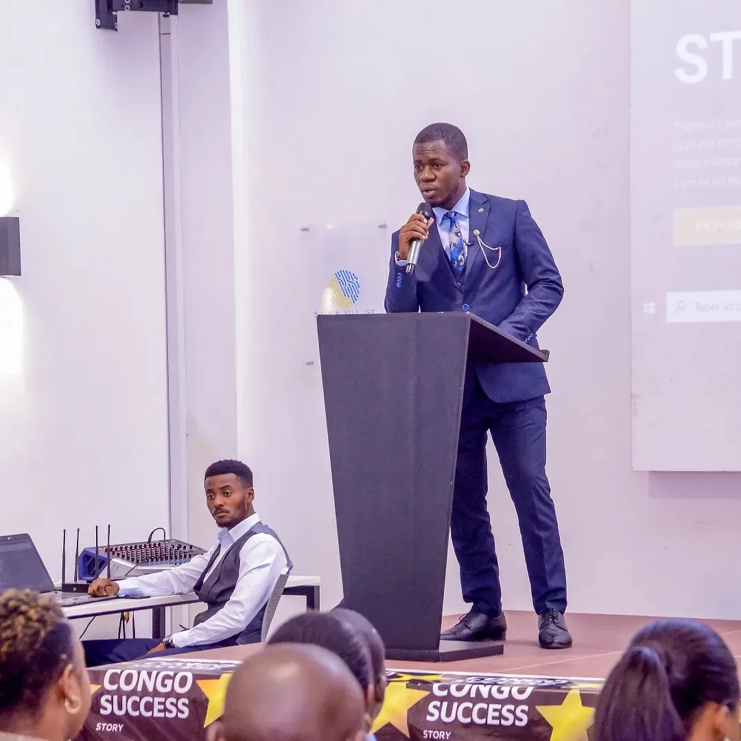 Trésor Dimandja s’exprimant au microphone derrière un pupitre.