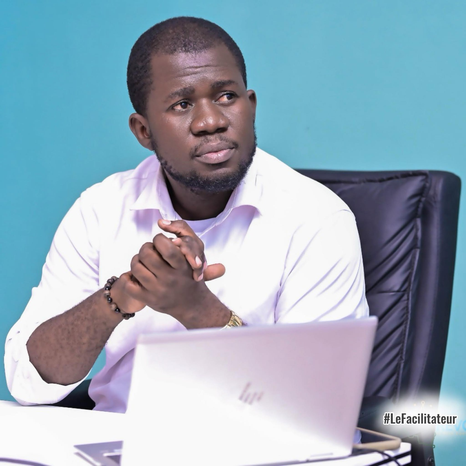 Trésor Dimandja seated in front of a laptop with his hands together.